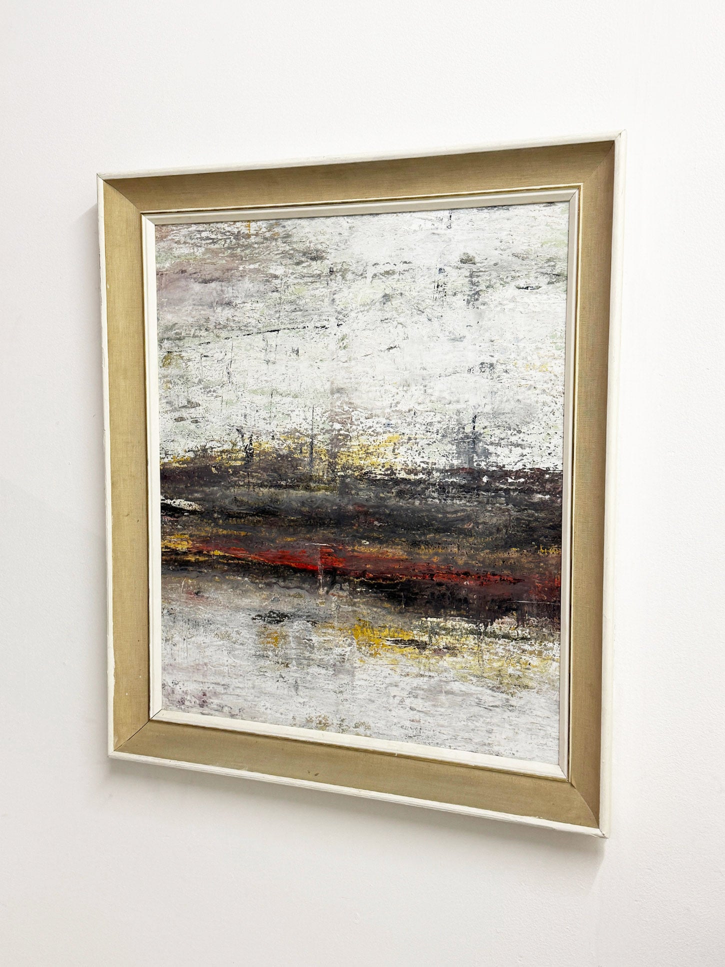 Large textured abstract acrylic painting in white, grey, earthy tones with subtle yellow and red, framed in mid-century white wood and linen.